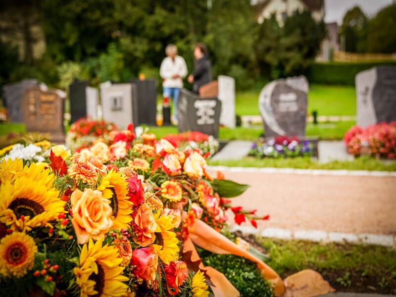 Blumengesteck auf dem Friedhof, im Hintergurnd Grabmahle
