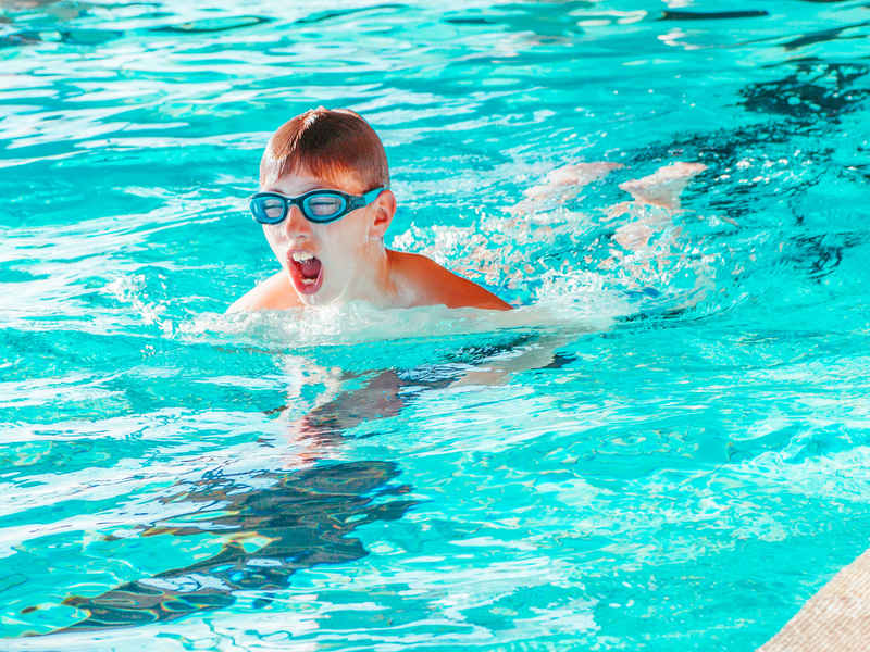 Junge schwimmt im Hallenbad