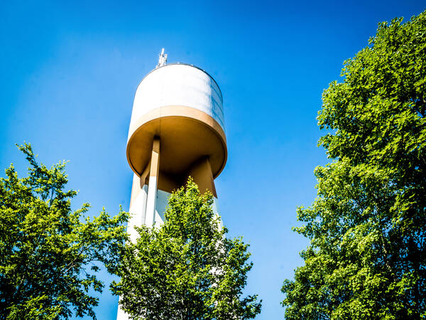 Wasserturm von Außen mit Bäumen im Vordergrund